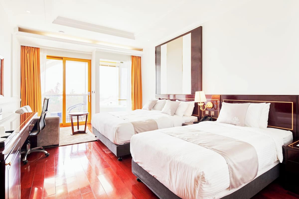 A hotel room with two beds, a desk, and a chair.