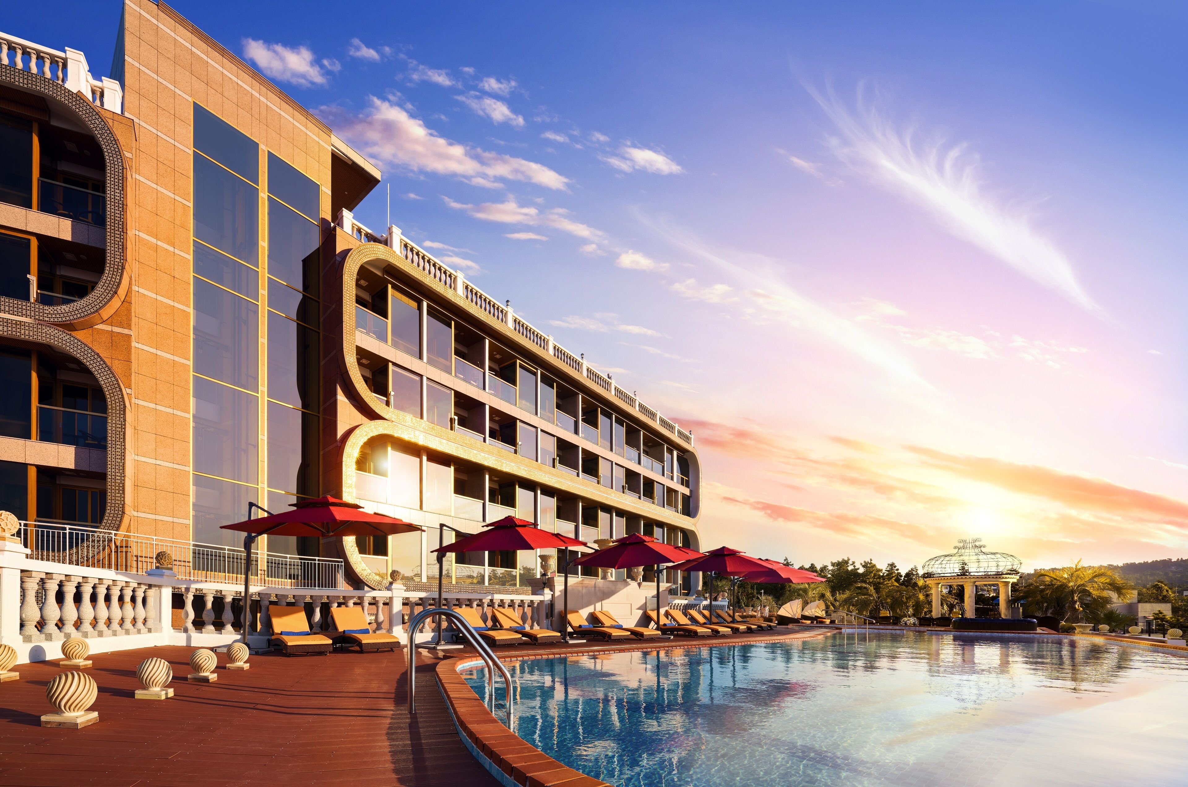 Un hotel con piscina, tumbonas y sombrillas.