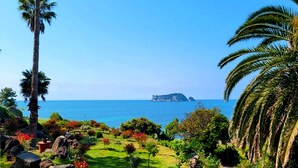 A pathway leading to a coastal area with palm trees and a view of the sea. - GoldOne Hotel & Suites (Seogwipo)