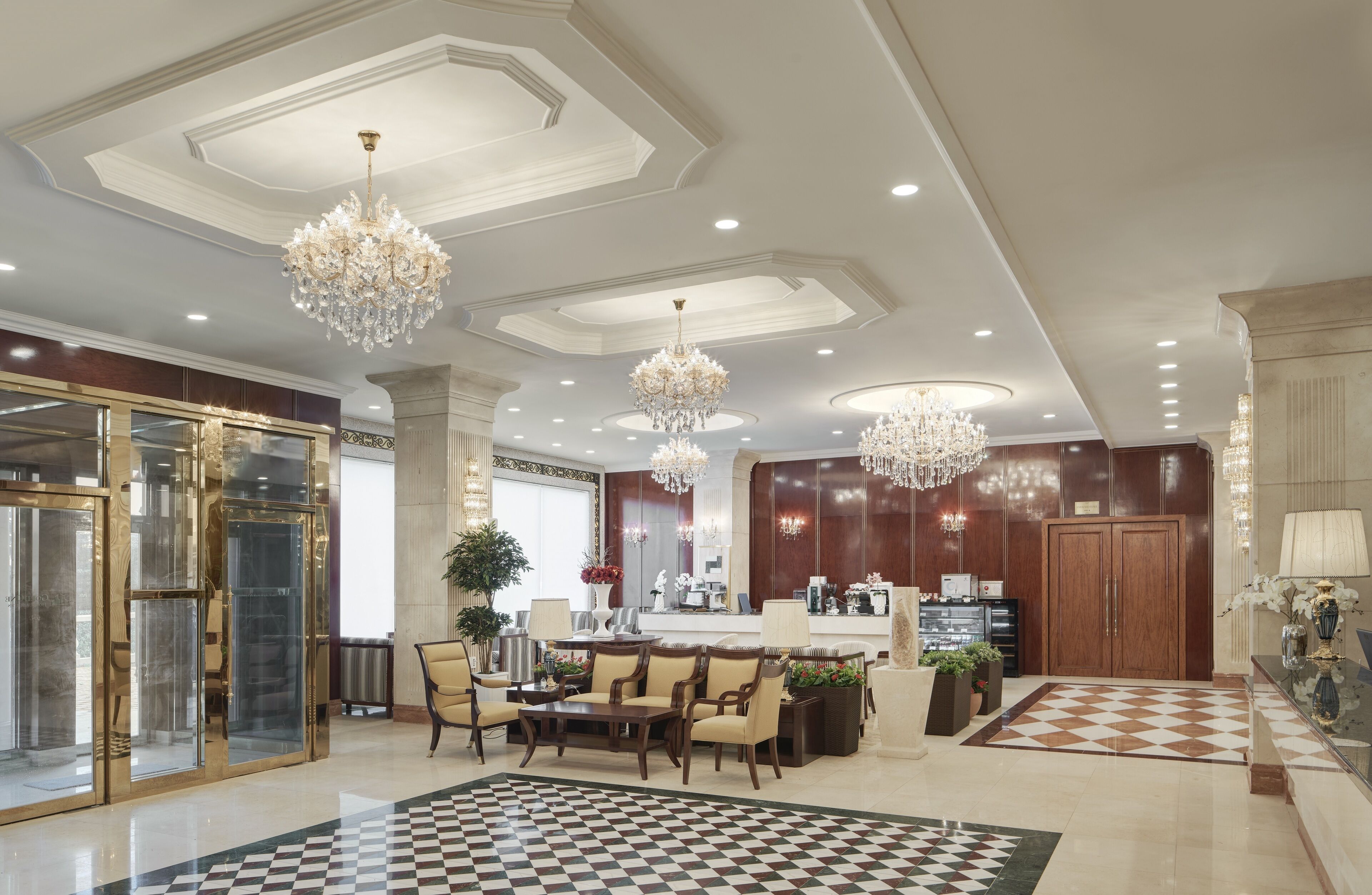 A spacious lobby with a checkered floor, a reception desk, and a bar area.