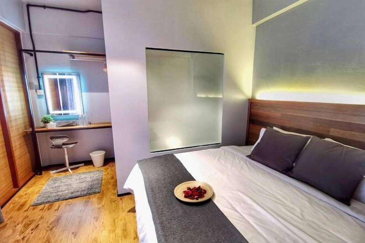 Ein modernes Hotelzimmer mit Bett, Nachttisch und einem großen Fenster.