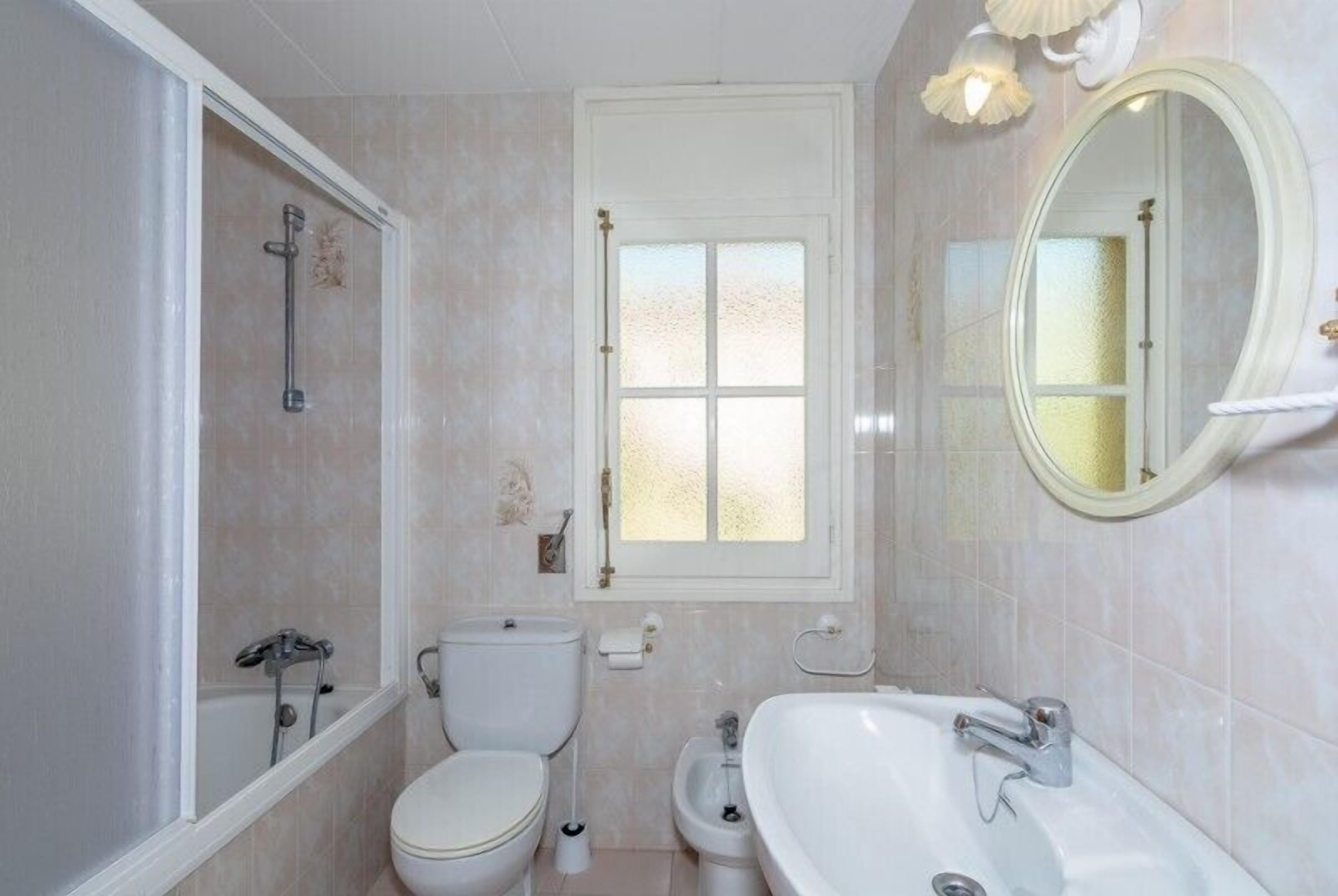 Een badkamer met toilet, bidet, badkuip en een raam met gezandstraald glas.
