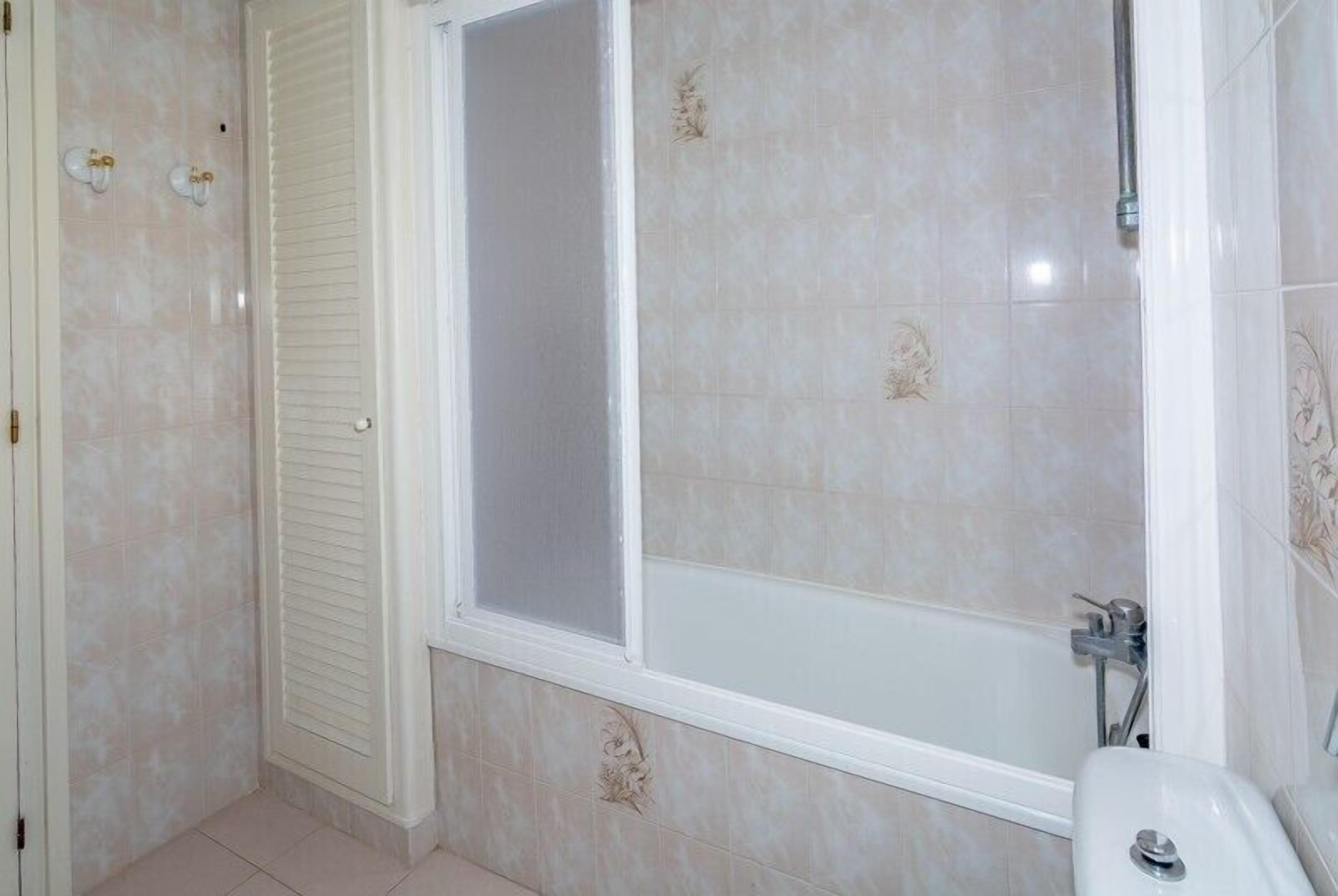 A bathroom with a shower, toilet, and a door with a window.