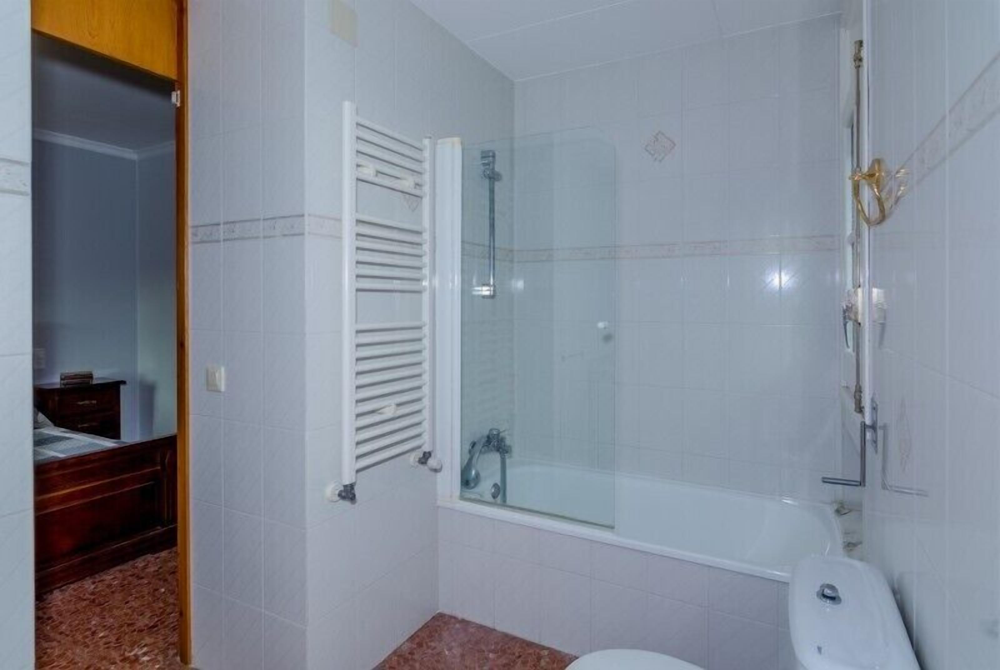 Un baño con ducha de vidrio, inodoro blanco y armario de madera.