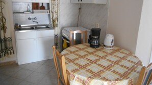 A small kitchen with a sink, stove, and cabinets. There is a table with chairs and a coffee maker. - Apartments in Heviz / Thermal Lake / Hungary (HÉVÍZ)
