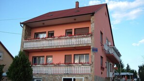 A multi-story building with balconies, a stone facade, and a red roof. - Apartments in Heviz / Thermal Lake / Hungary (HÉVÍZ)