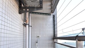 A compact, modern bathroom with a white tiled wall, a large white water heater, and a visible window offering a view of the outside. - Love Taipei - Ximen (Taipei)