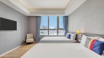 A hotel room with a large bed, a chair, a television, and a window with a city view.