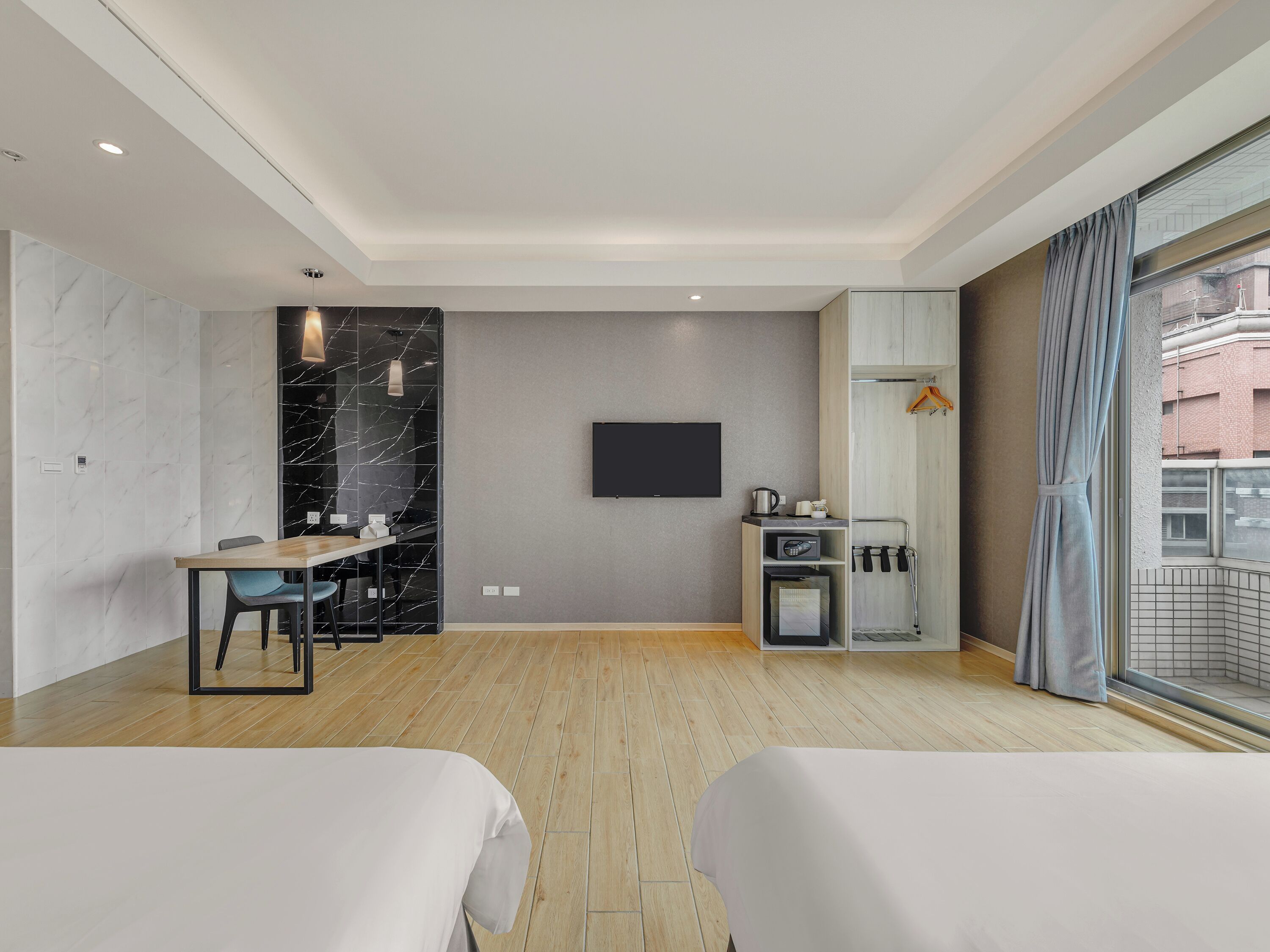 Ein modernes Hotelzimmer mit Flachbildfernseher, Essbereich, Küchenzeile und einem Balkon mit Blick.