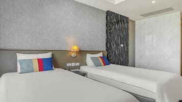 A hotel room with two beds, a wall-mounted lamp, and a large wardrobe.
