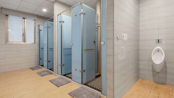 A modern restroom with multiple stalls, a urinal, and a checkered floor pattern.