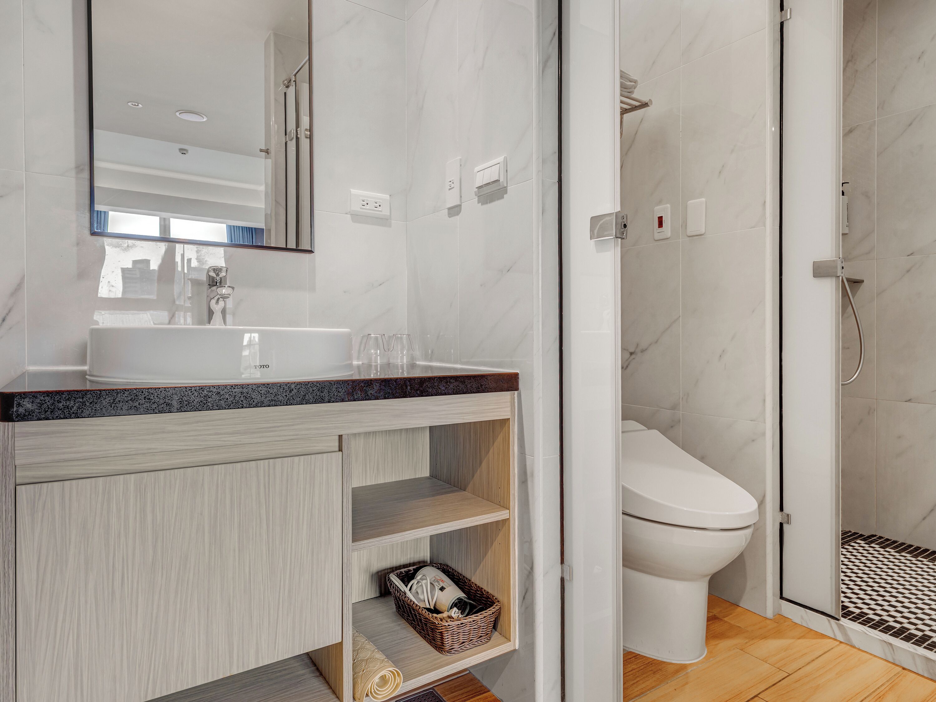 A modern bathroom with a marble sink, a toilet, and a shower area.