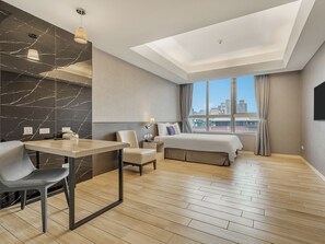 A modern hotel room with a bed, a desk, a chair, a nightstand, and a large window with a city view. - CHECK inn New Taipei LuZhou (New Taipei City)