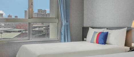 Quarto de hotel com uma janela grande, cama com roupa de cama branca e parede cinzenta com textura.