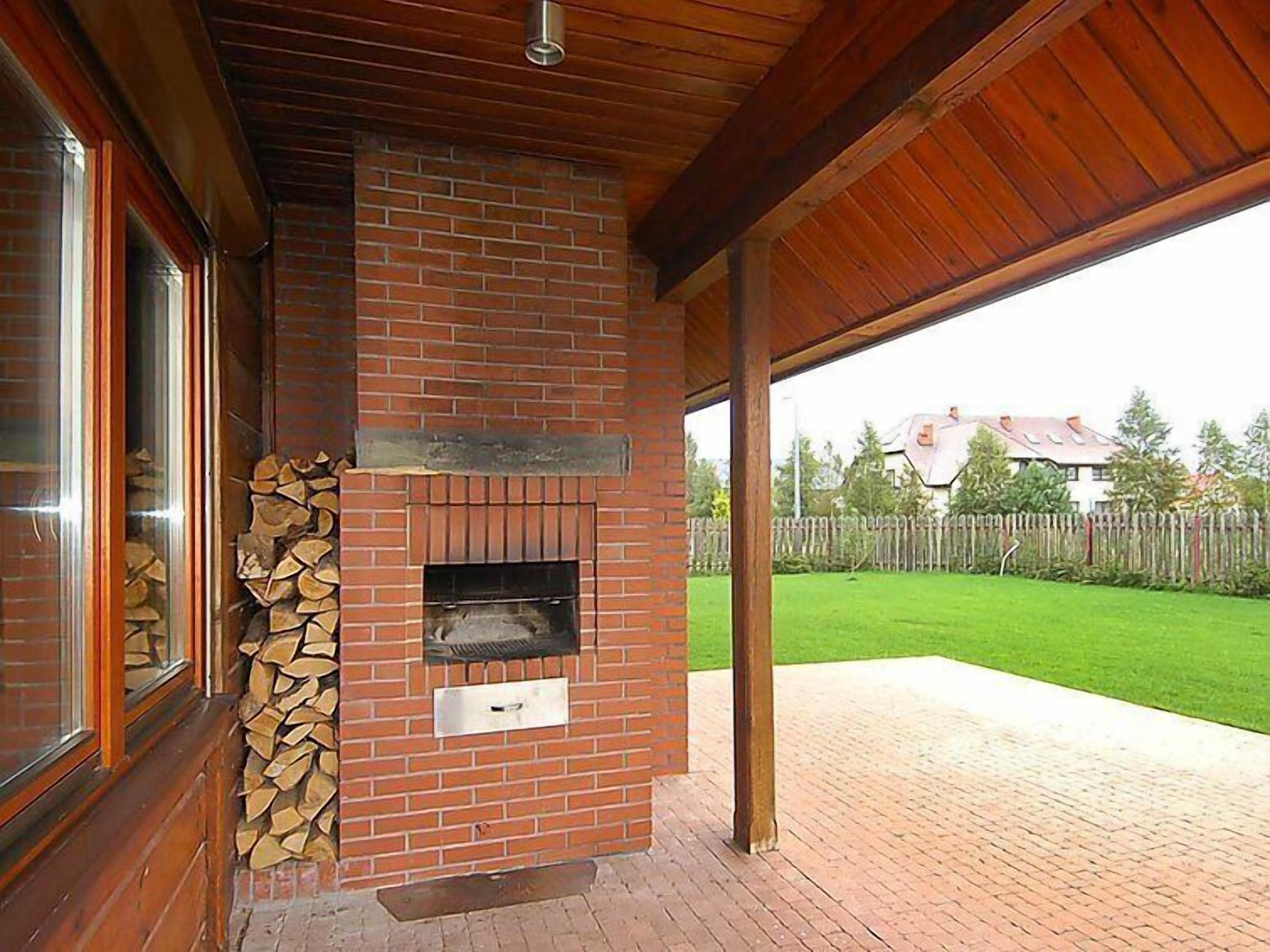 Ein Kamin aus Ziegelsteinen mit Metallklappe, ein Holzstoß und ein Fenster mit Jalousien.