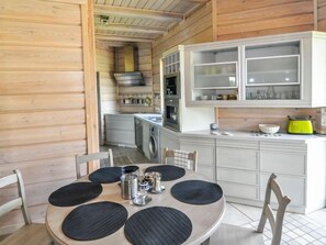 A modern kitchen with wooden walls, a dining area with a round table and chairs, and a bright yellow toaster.