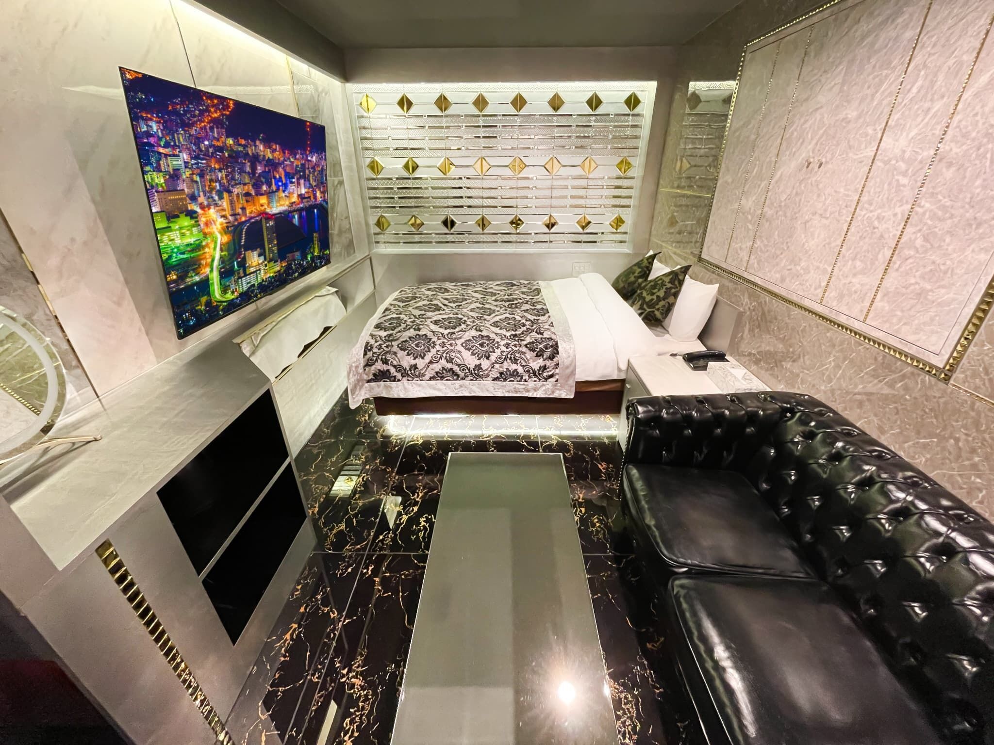 A modern bedroom with a bed, a TV, a sofa, and a decorative wall panel.