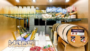 Un espace bar agrémenté d’une pancarte « Bienvenue », de coupes à champagne, de bouteilles et d’un tonneau en bois muni de robinets.