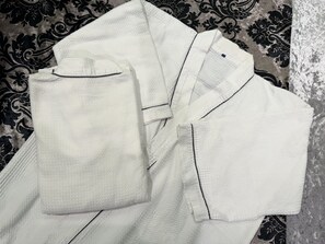 A neatly folded white shirt with a collar and button placket, placed on a patterned fabric background. - Hotel Rocks (Tokyo)