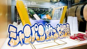 A food display with a yellow stand, a bottle, and a blue sign with Chinese characters. - Hotel Rocks (Tokyo)