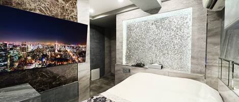 Habitación de hotel moderna con vistas a la ciudad, una cama grande y un revestimiento de pared con textura original.