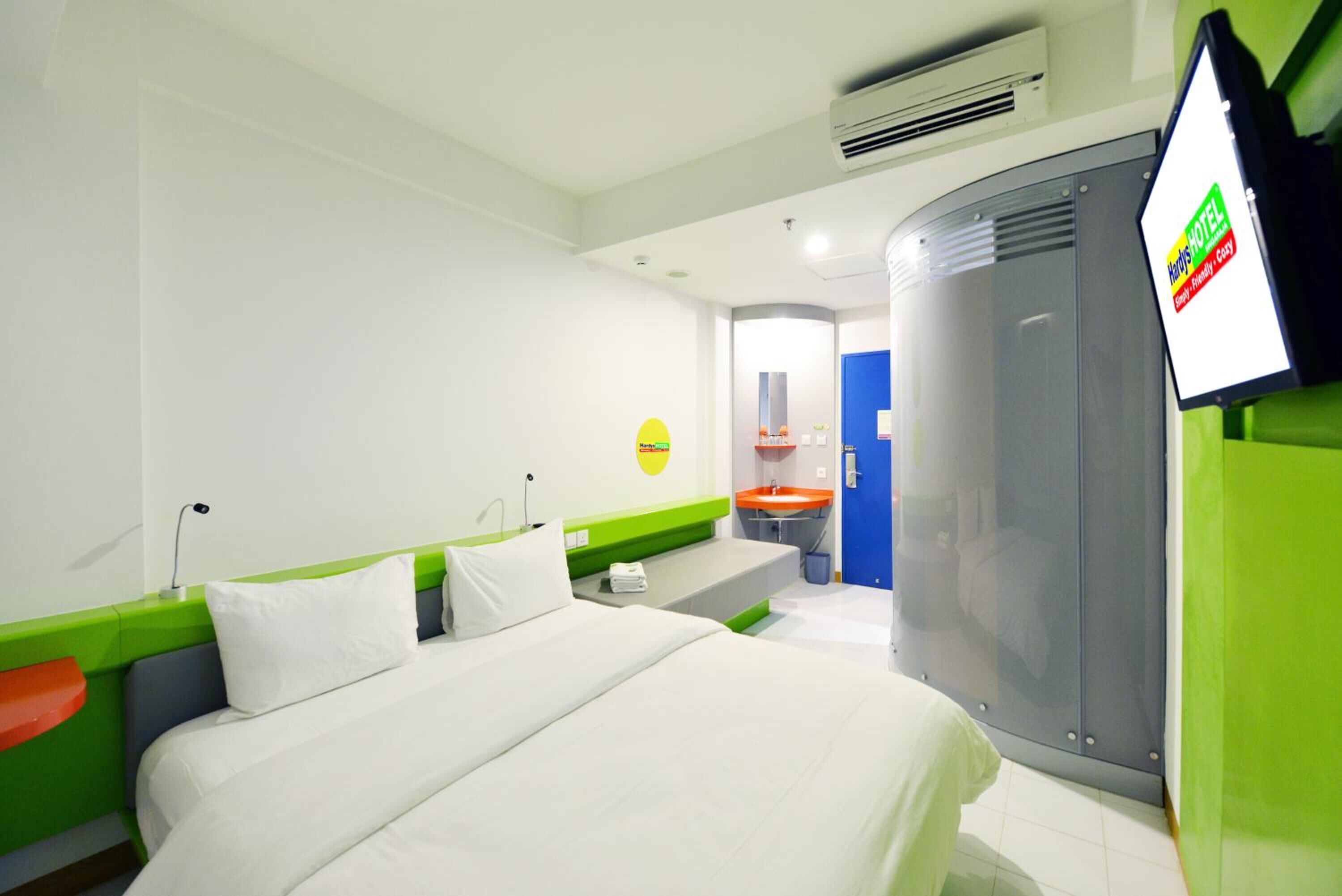Una habitación de hotel con cama, escritorio, espejo y televisión.