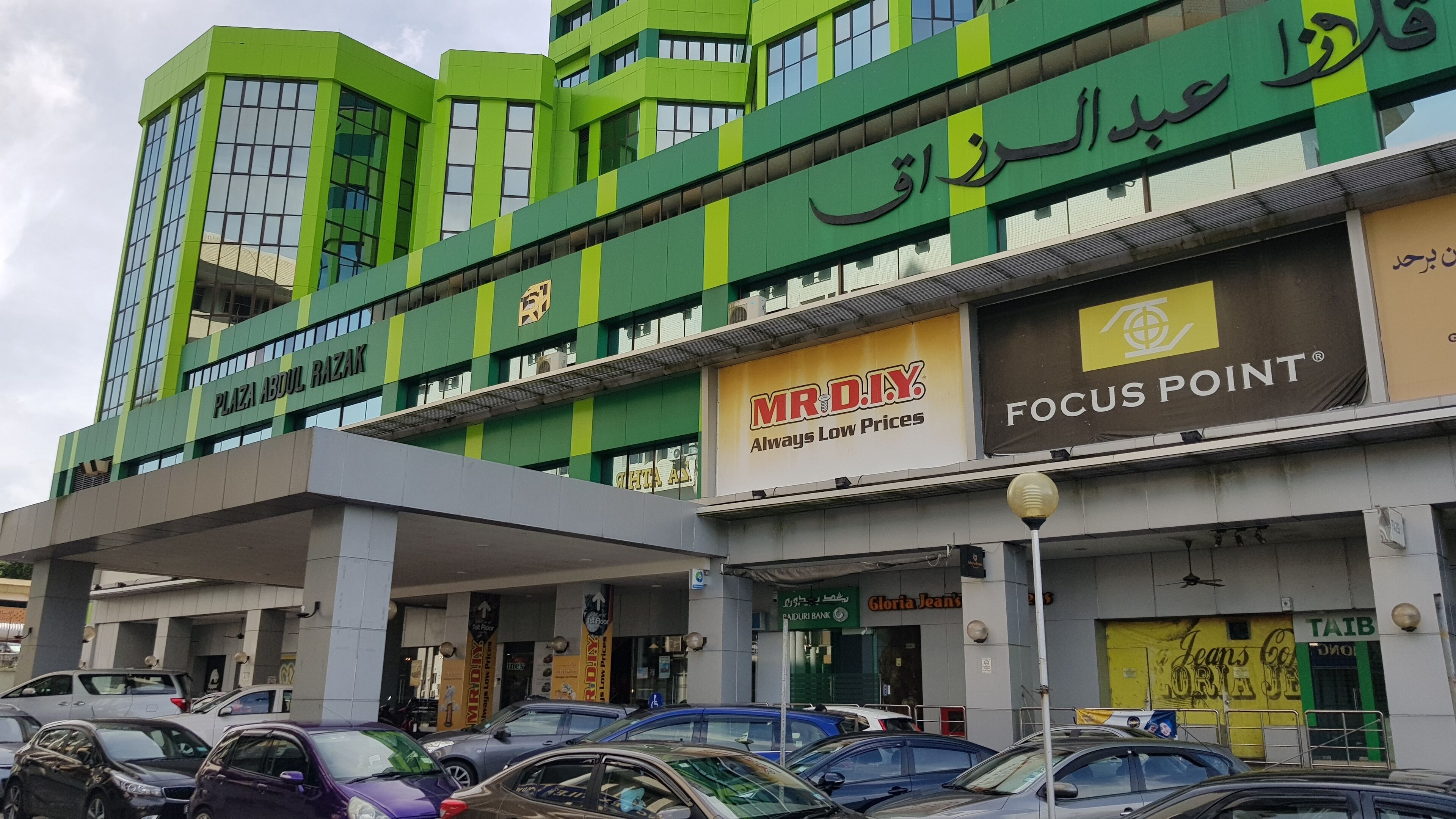 A multi-story commercial building with various storefronts, including a bank and retail stores.