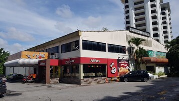Un edificio de dos pisos con un restaurante Jollibee en la planta baja.