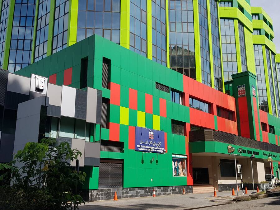A modern building with a green and red facade, large windows, and a sign indicating it is a business center.