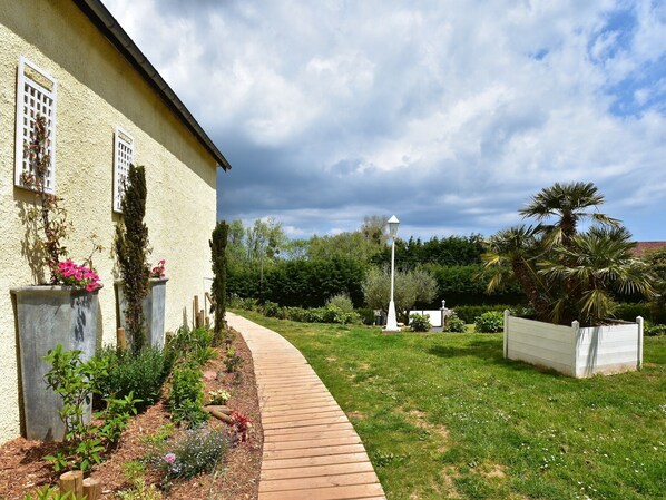 A pathway leading to a house with a garden, a white fence, and a street lamp.