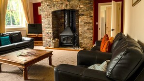 Ein Wohnzimmer mit Kamin aus Stein, Ledersofas, einem Holztisch und einem Fernseher.