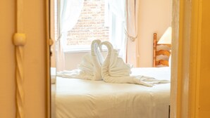 Ein Hotelzimmer mit einem Bett, einem Holzkopfteil, einer Lampe und einer durch das Fenster sichtbaren Ziegelwand.