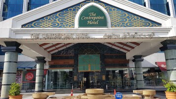 Entrada del Centropoint Hotel, con un letrero verde, fachada de mármol y columnas.