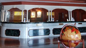 A grand lobby with a marble reception desk, a globe on a stand, and a chandelier. - The Centrepoint Hotel (Bandar Seri Begawan)