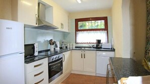 A compact kitchen with white cabinets, a built-in oven, a microwave, and a sink. - Club Villamar - Nice villa with airco, wifi, fenced private swimming pool nearby Calonge (Calonge)