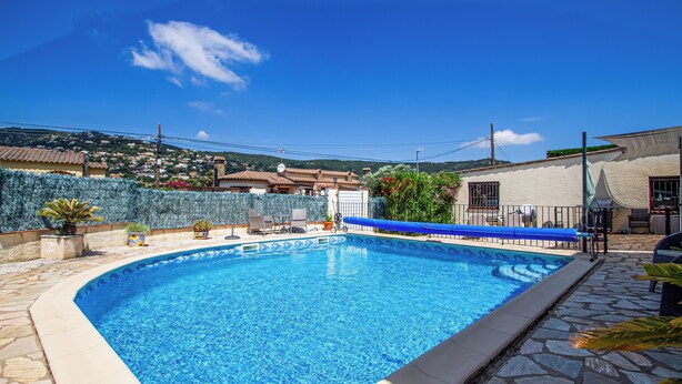A swimming pool with a stone border, surrounded by a patio area with chairs and a table. - Club Villamar - Nice villa with airco, wifi, fenced private swimming pool nearby Calonge (Calonge)