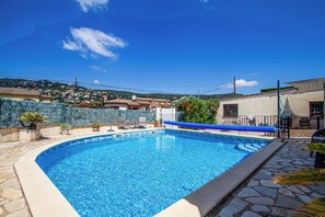 A swimming pool with a stone border, surrounded by a patio area with chairs and a table. - Club Villamar - Nice villa with airco, wifi, fenced private swimming pool nearby Calonge (Calonge)