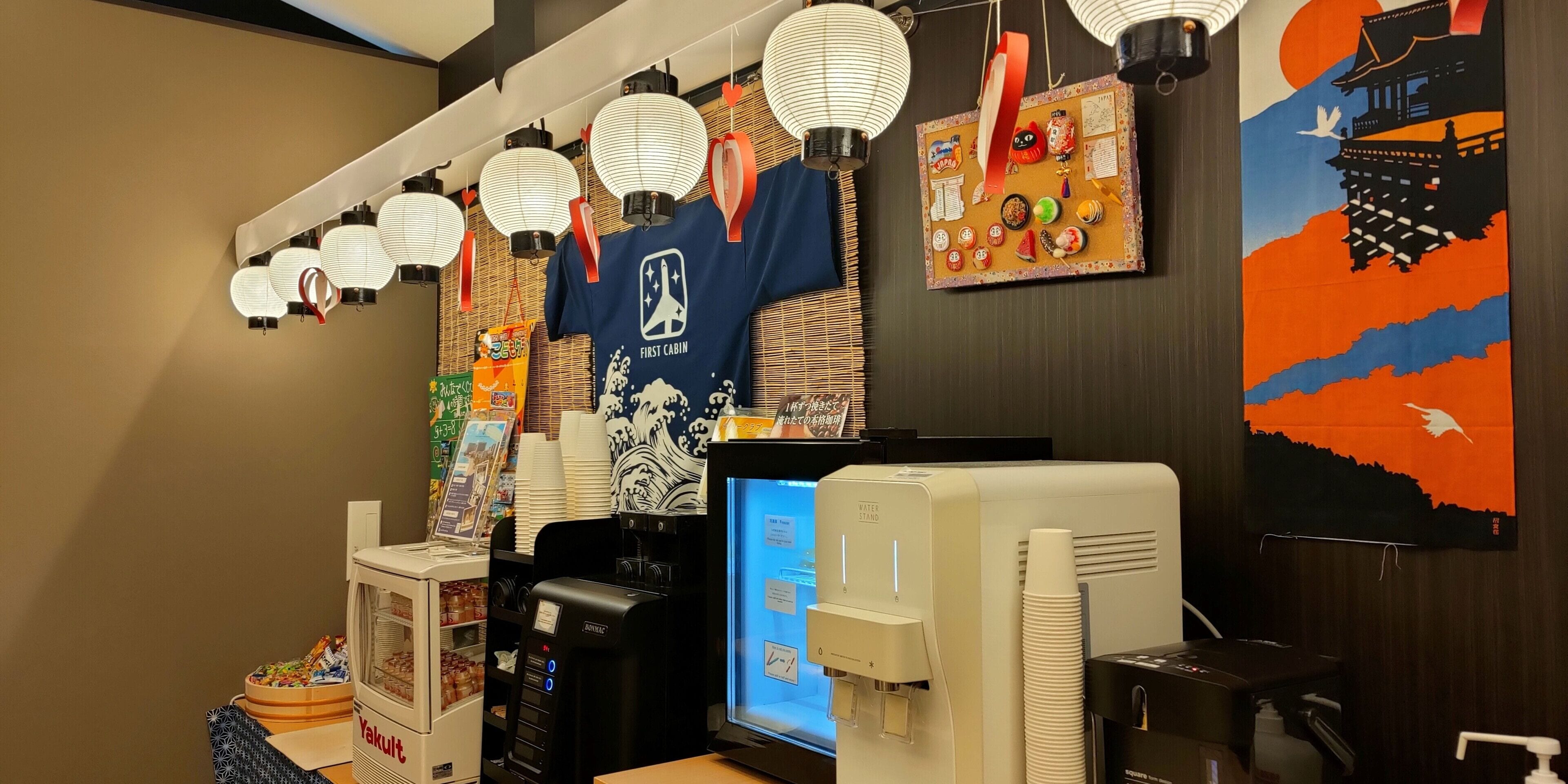 A room with a water dispenser, a vending machine, and a digital screen.