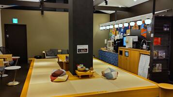 Un vestíbulo de hotel con esteras de tatami, una recepción y una zona de estar con cojines.