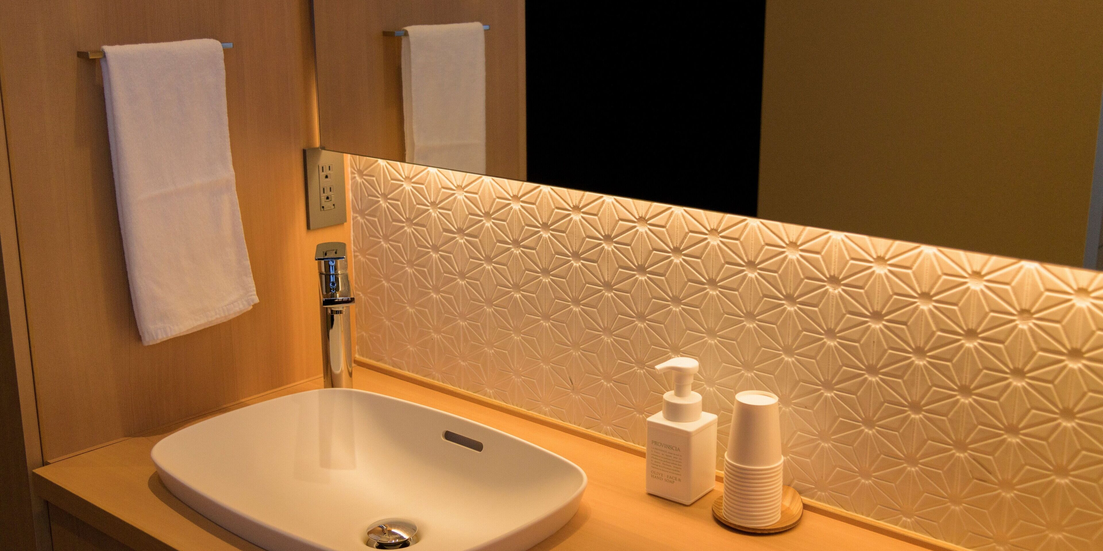 A bathroom with a white sink, a mirror, and a towel rack.