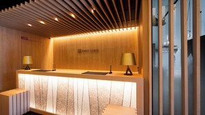 A reception desk with a wooden finish, two lamps, and a sign that reads "First Cabin". - First Cabin Kyoto Nijojo (Kyoto)