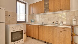 A kitchen with wooden cabinets, a built-in oven, a sink, and a window with curtains.
