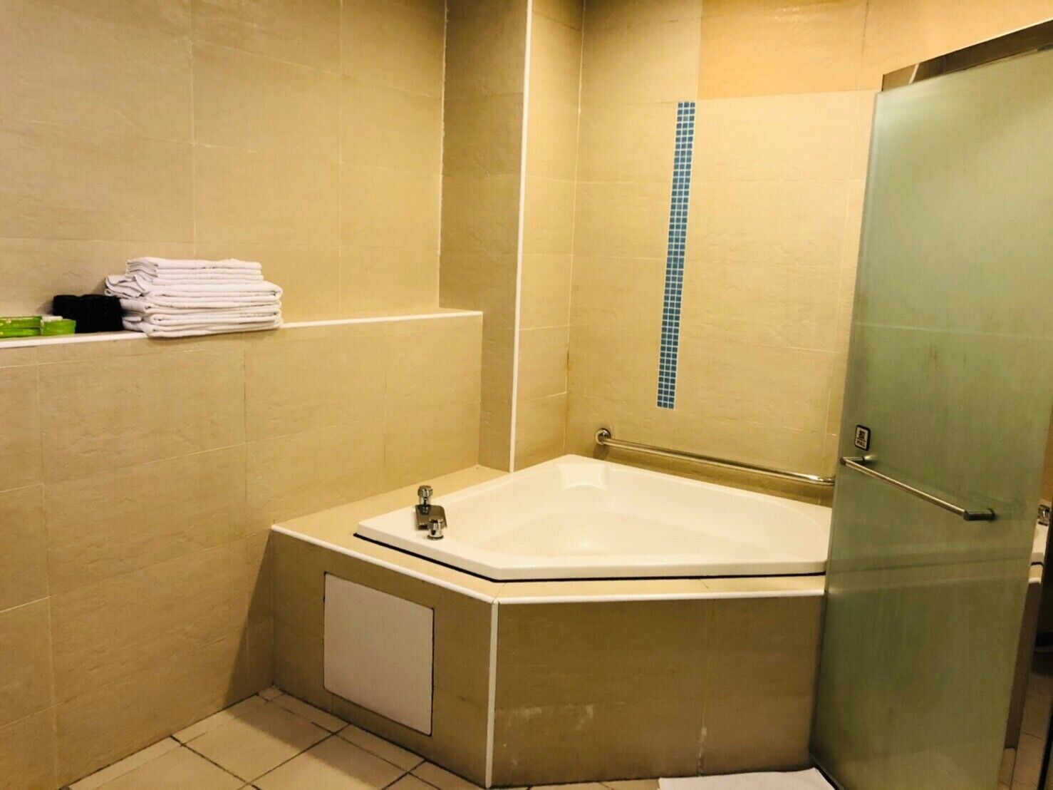A bathroom with a bathtub, a glass shower enclosure, and a towel rack with folded towels.