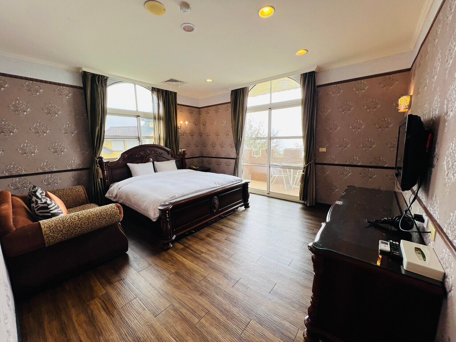 A hotel room with a large bed, a desk, a chair, and a TV.