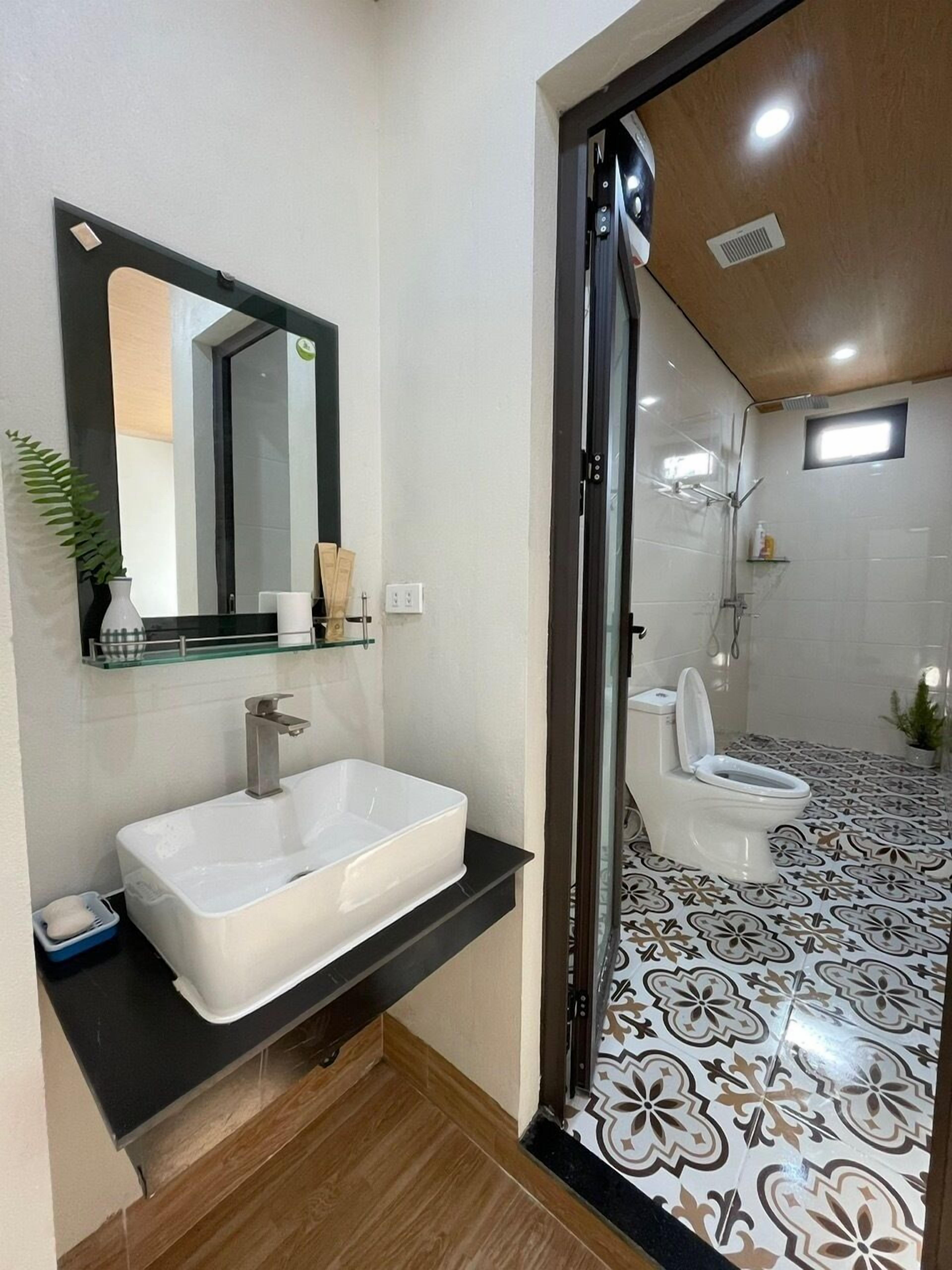 A modern bathroom with a white sink, mirror, and toilet.