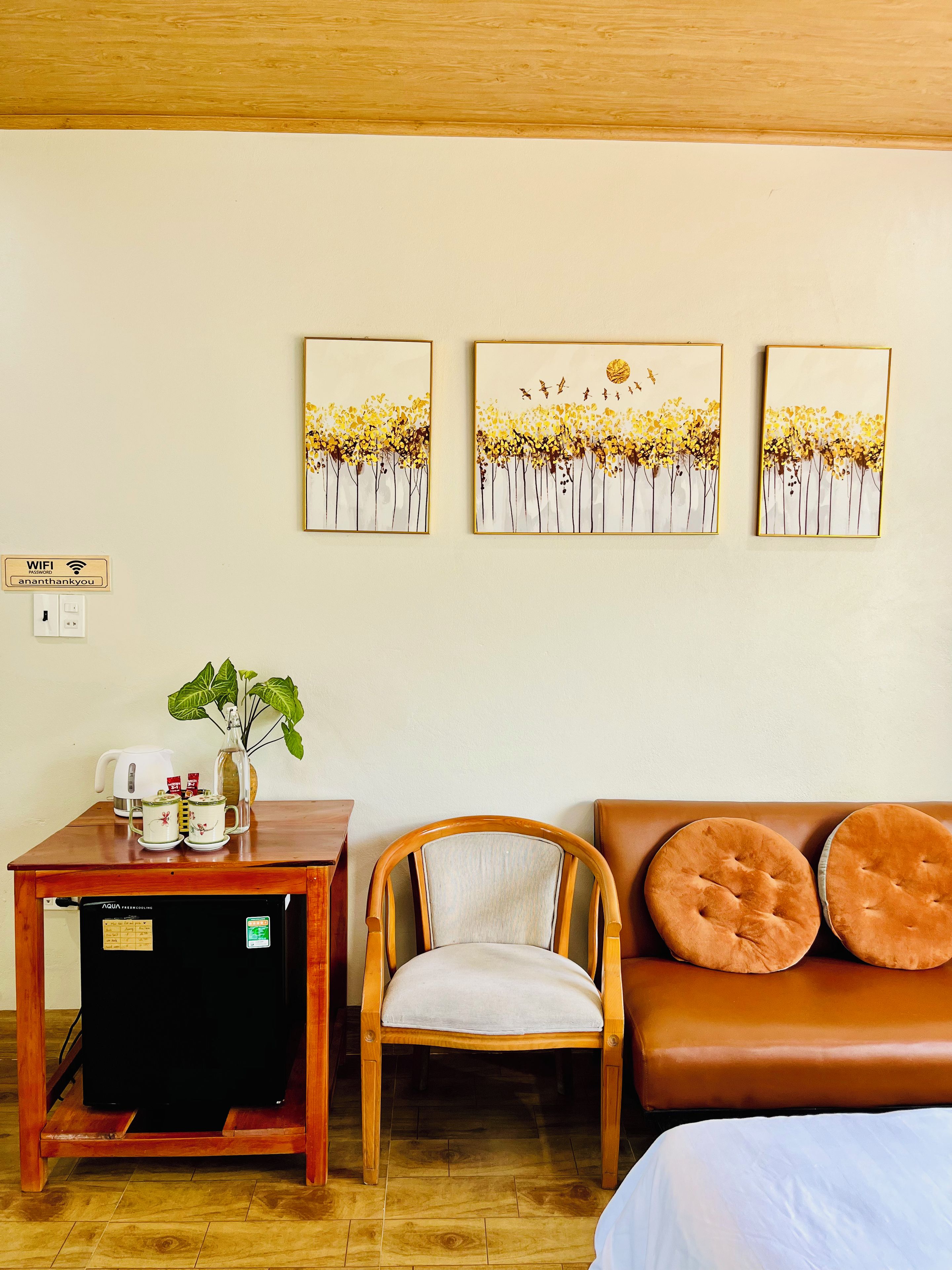 Habitación de hotel con una mesa de madera, una silla, un sofá y tres cuadros colgados en la pared.