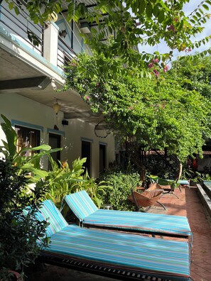 A courtyard with lounge chairs, a hammock, and a variety of plants. - Phong Nha An An Homestay (Phong Nha)