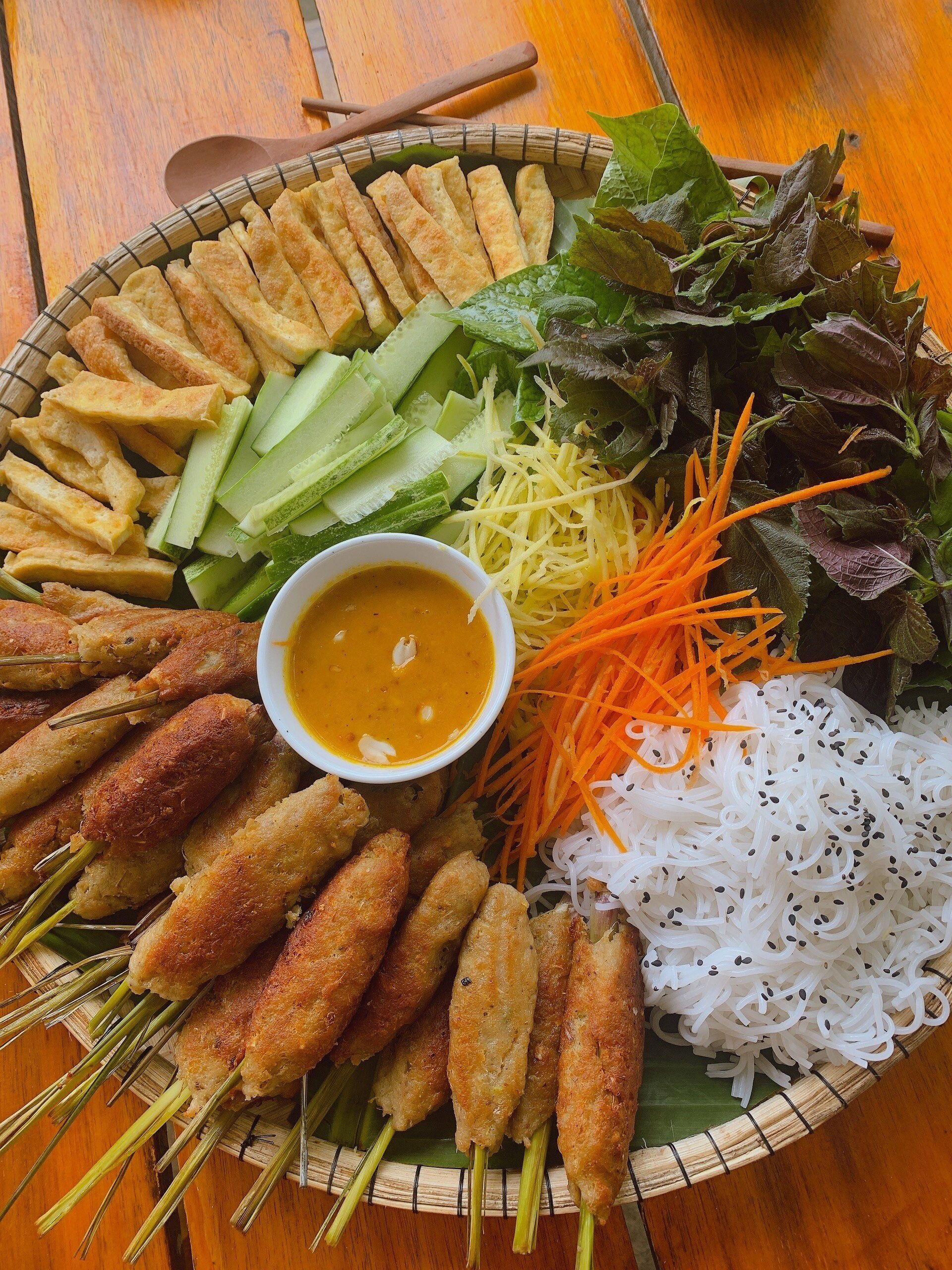 Un plato de comida con diversos ingredientes, incluyendo alimentos fritos, verduras y fideos.