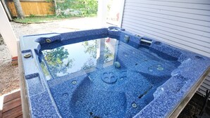 A hot tub with a glass top, surrounded by a wooden deck and a white exterior wall. - Cool Updated Craftsman Bungalow (Austin)