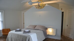 A bedroom with a bed, a nightstand, a chair, and a ceiling fan. - Cool Updated Craftsman Bungalow (Austin)